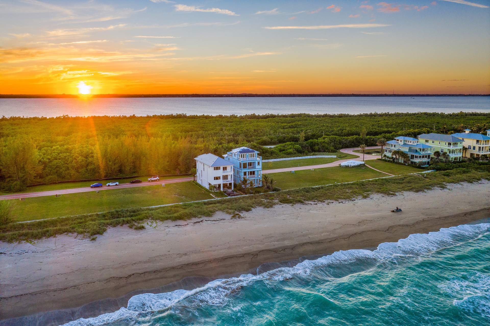 Home lining the beach with bright orange sunset behind it.